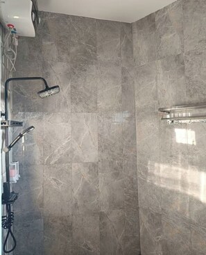 Ein Duschbereich mit Handbrause und am Wand montiertem Wasserhahn.