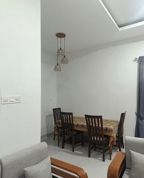 Ein Essbereich mit Tisch, Stühlen, einer Pendelleuchte und einer Couch.