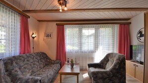 Ein Wohnzimmer mit zwei gemusterten Sofas, einem Holztisch und einem Fernseher auf einer Holzkommode.