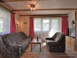 Ein Wohnzimmer mit zwei gemusterten Sofas, einem Holztisch und einem Fernseher auf einer Holzkommode.