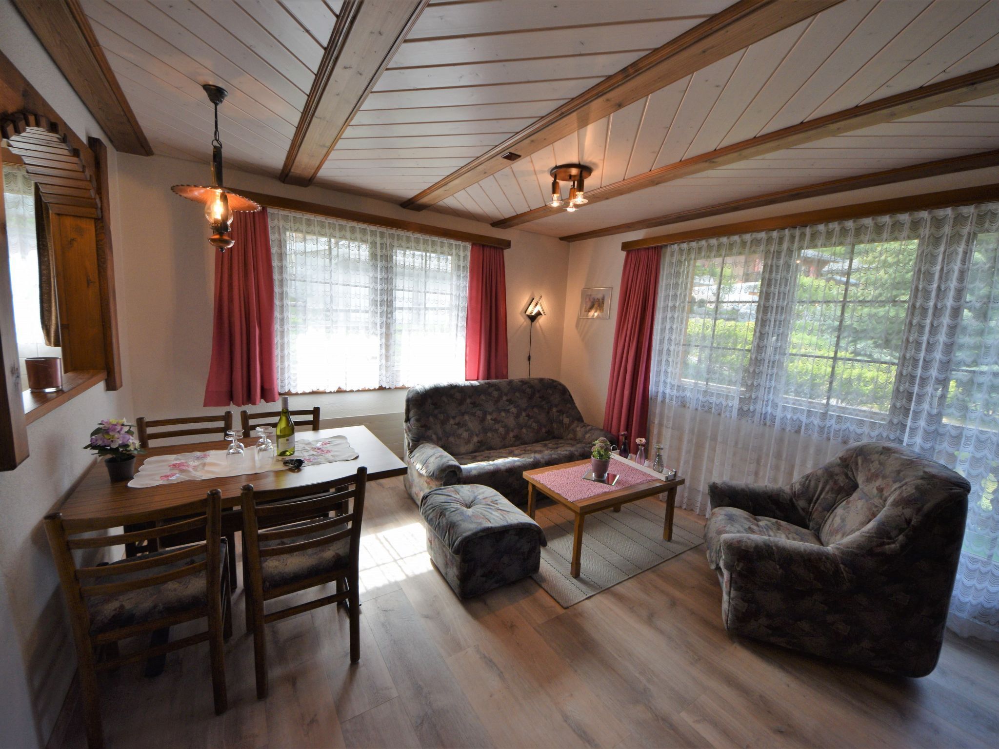 Una sala de estar acogedora con techo de madera, una mesa de comedor con sillas, un sofá y una pequeña mesa de centro.