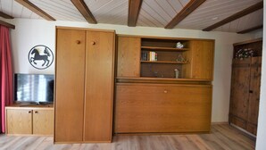 Ein Zimmer mit Holzschrank, Fernseher und Holzgarderobe.