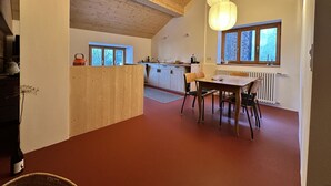 A modern kitchen with wooden beams, a dining area with a table and chairs, and large windows providing natural light.