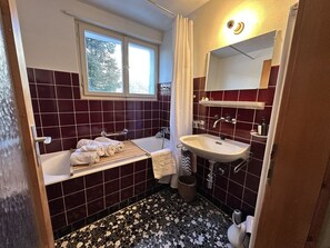 Ein Badezimmer mit Badewanne, Waschbecken und Fenster.