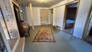Ein Zimmer mit einem hölzernen Schminktisch, einem Spiegel, einem Teppich und einem Bett im angrenzenden Raum.