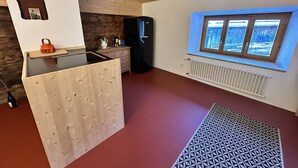 A compact kitchen with a built-in refrigerator, a window with a view, and a wooden partition.