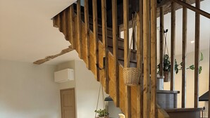 A wooden staircase with a rustic design, a dining area with a table and chairs, and a potted plant on a small stand. - Le Clos des Murmures - maisonnette mitoyenne à Trept (Trept)