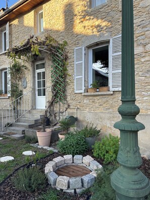 A stone building with a wooden door, white shutters, and a stone staircase leading to the entrance. - Le Clos des Murmures - maisonnette mitoyenne à Trept (Trept)