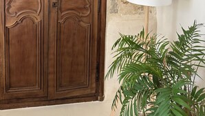 A wooden wardrobe with intricate carvings, a white lamp, and a potted plant. - Le Clos des Murmures - maisonnette mitoyenne à Trept (Trept)