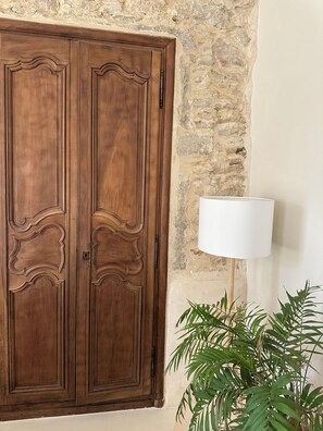 A wooden wardrobe with intricate carvings, a white lamp, and a potted plant. - Le Clos des Murmures - maisonnette mitoyenne à Trept (Trept)