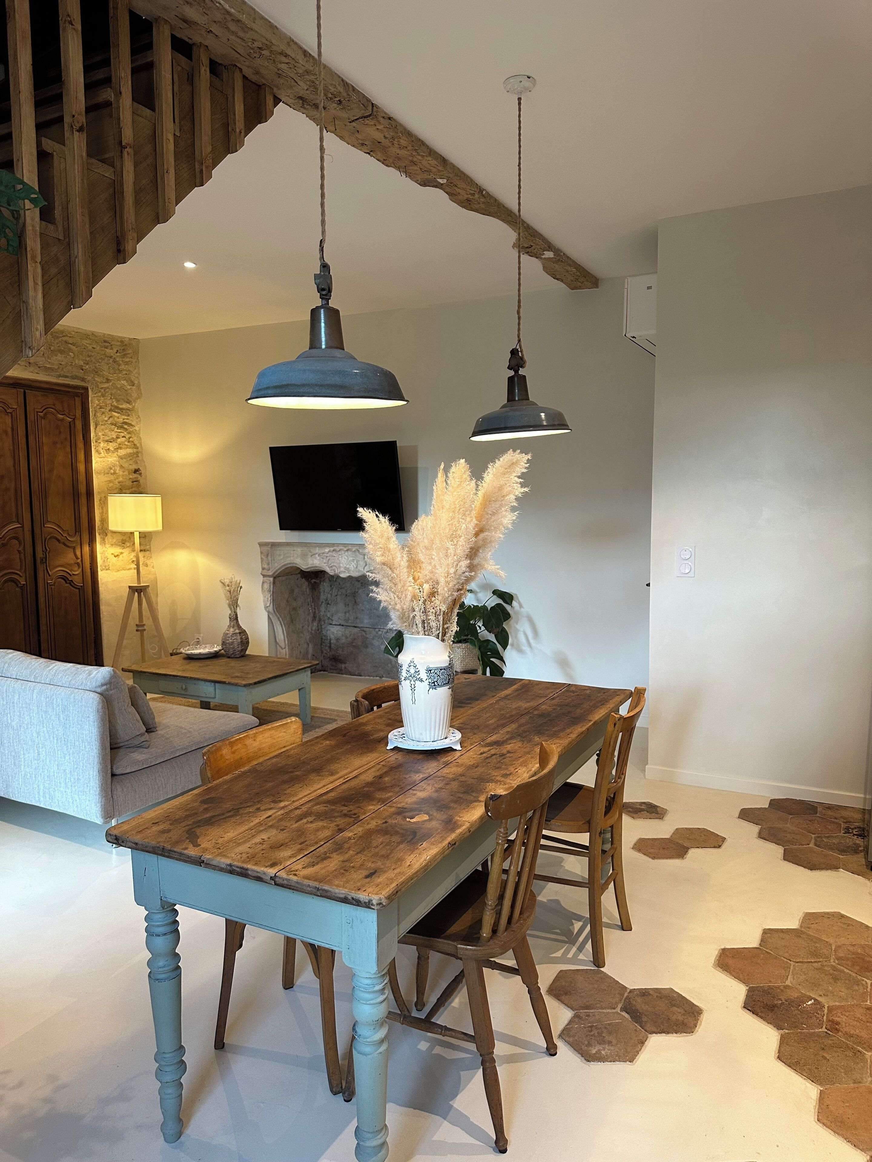 Uma sala de jantar com mesa de madeira, cadeiras e luminárias pendentes.
