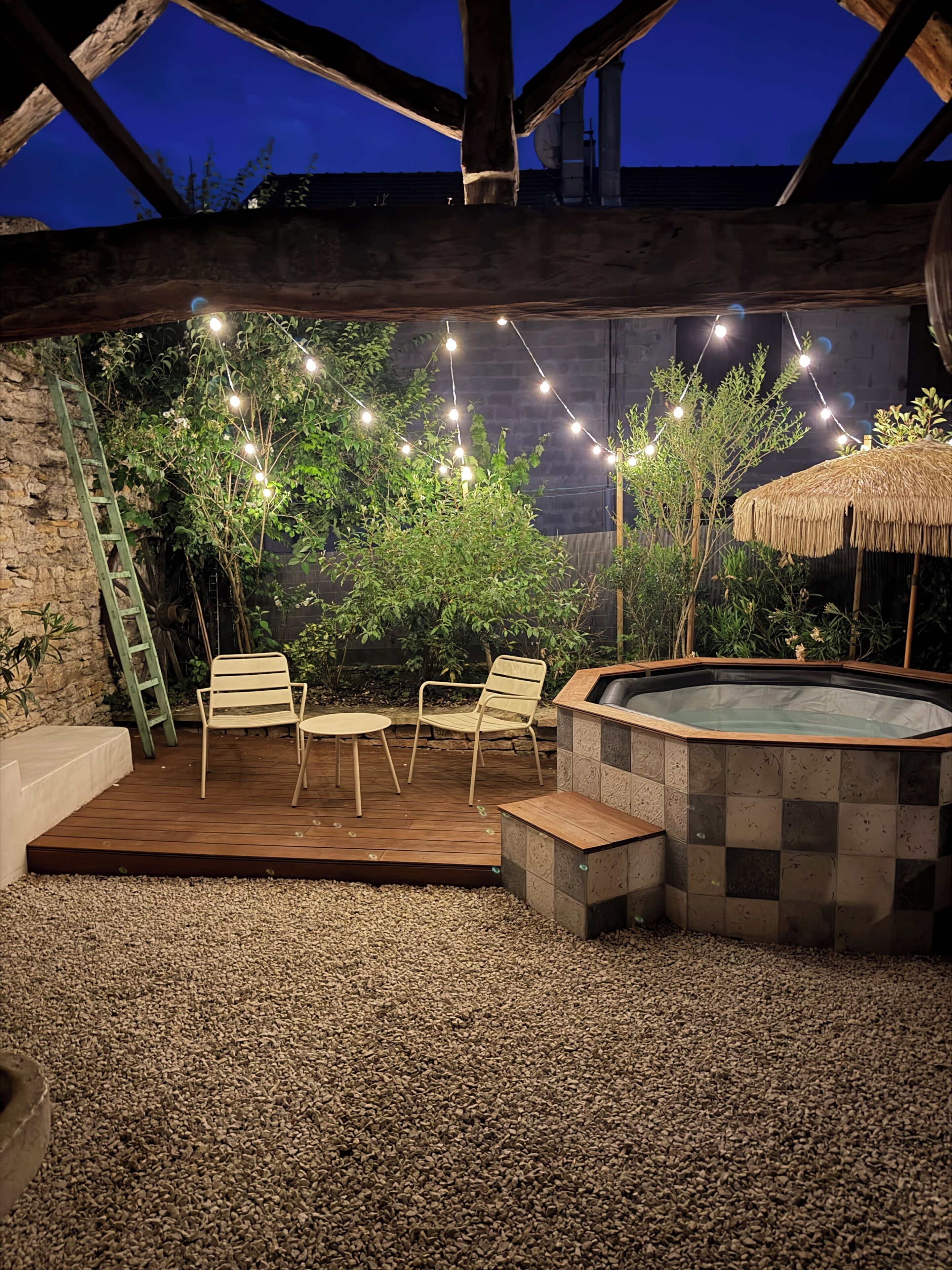 An outdoor patio with a hot tub, string lights, and seating.