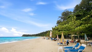 A beach with sun loungers and umbrellas, a clear sky, and a calm sea. - Stylish 1BR Apartment at The Title Halo, Nai Yang (Tambon Sa Khu)