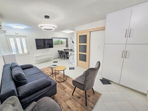 A modern living room with a sofa, a dining area with chairs and a table, and a kitchen area with cabinets and a TV. - Lux Adriatica 1 by Interhome (Trogir/Okrug Gornji)