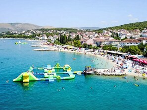 A coastal town with a beach, inflatable water structures, and a clear blue sea. - Lux Adriatica 1 by Interhome (Trogir/Okrug Gornji)