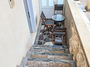 Eine Treppe mit Steinböden führt zu einer kleinen Sitzgelegenheit im Freien mit Tisch und Stühlen.