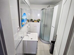 Un baño moderno con lavamanos, espejo y armarios blancos.
