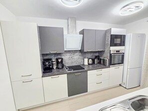 A modern kitchen with white cabinets, a built-in microwave, a coffee machine, and a refrigerator. - Lux Adriatica 3 by Interhome (Trogir/Okrug Gornji)