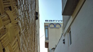 A narrow alleyway with a woven wall on one side and a building with a sign reading 'Safiya Hotel' on the other. - Authentic and Traditional Bukhara designed hotel (Bukhara)