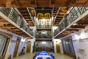 Un intérieur spacieux agrémenté d’un élément aquatique central, de poutres en bois et de balcons décoratifs.