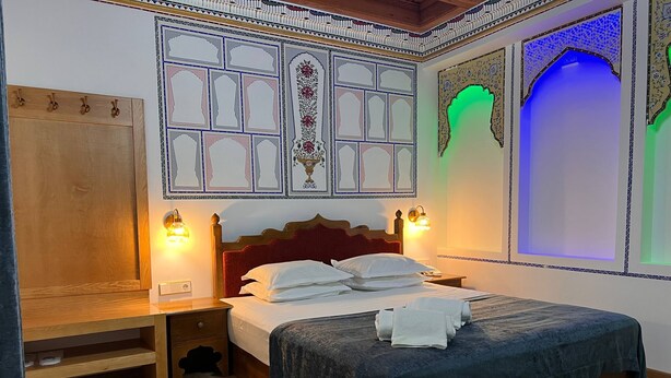 A hotel room with a wooden bed, two bedside tables, a nightstand, and a wardrobe. - Authentic and Traditional Bukhara designed hotel (Bukhara)