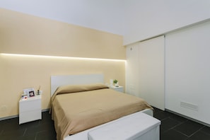 A modern bedroom with a bed, bedside tables, and a wardrobe. - 1743LOft Studio Alla Corte (Siracusa)