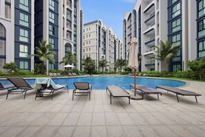 Ett poolområde med solstolar och palmer.