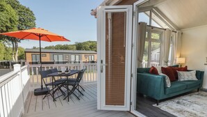 An open deck with a table and chairs, a sofa with cushions, and a large umbrella. - 73 CILDRAETH, pet friendly, country holiday cottage in Llanarth (New Quay)