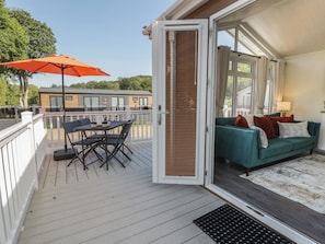 An open deck with a table and chairs, a sofa with cushions, and a large umbrella. - 73 CILDRAETH, pet friendly, country holiday cottage in Llanarth (New Quay)