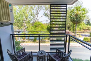 A balcony with wicker furniture, a view of a road, and greenery. - Cassia Residences Spacious 2BR with Lagoon View (Choeng Thale (Thalang District))