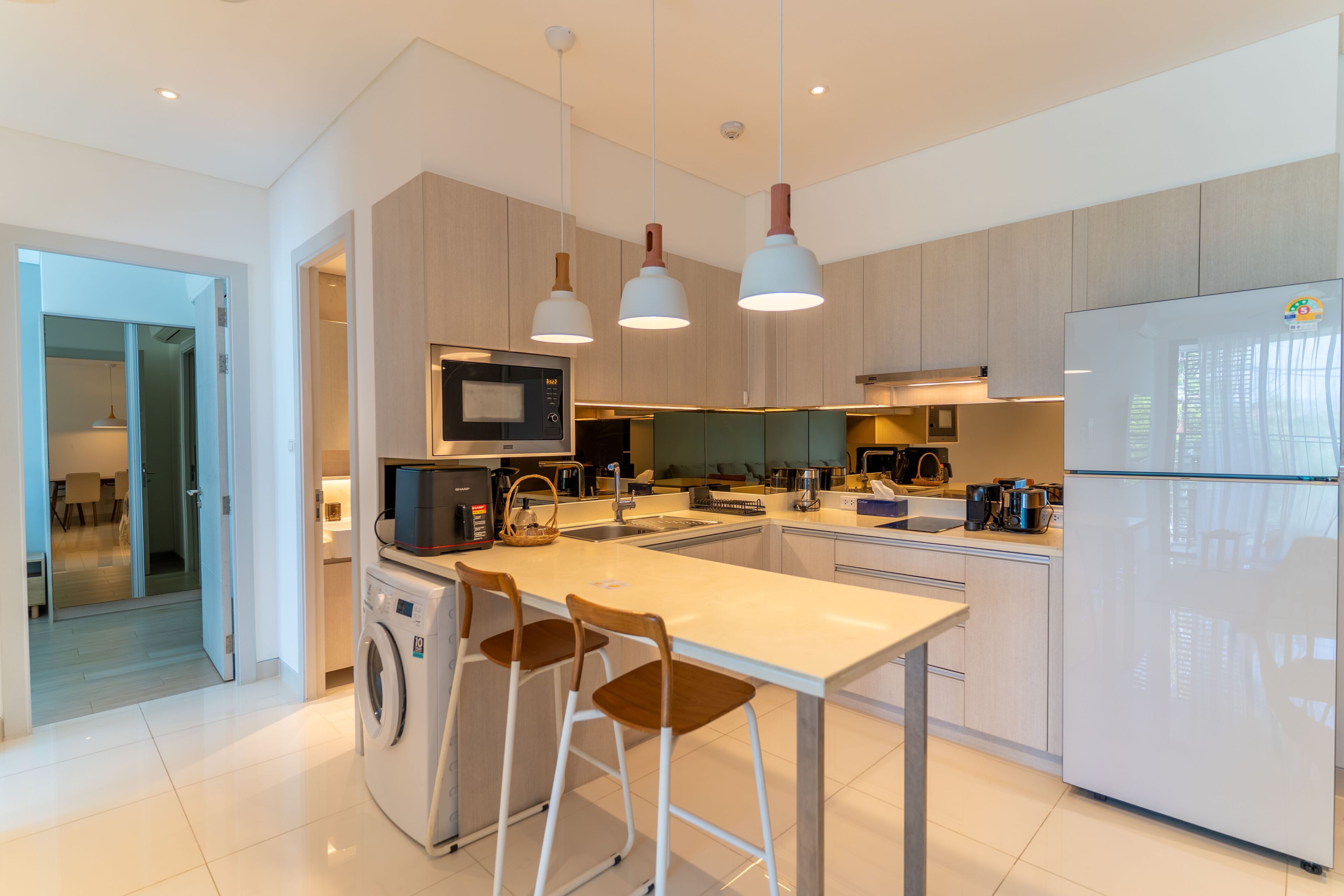 A modern kitchen with a central island, built-in appliances, and pendant lighting.