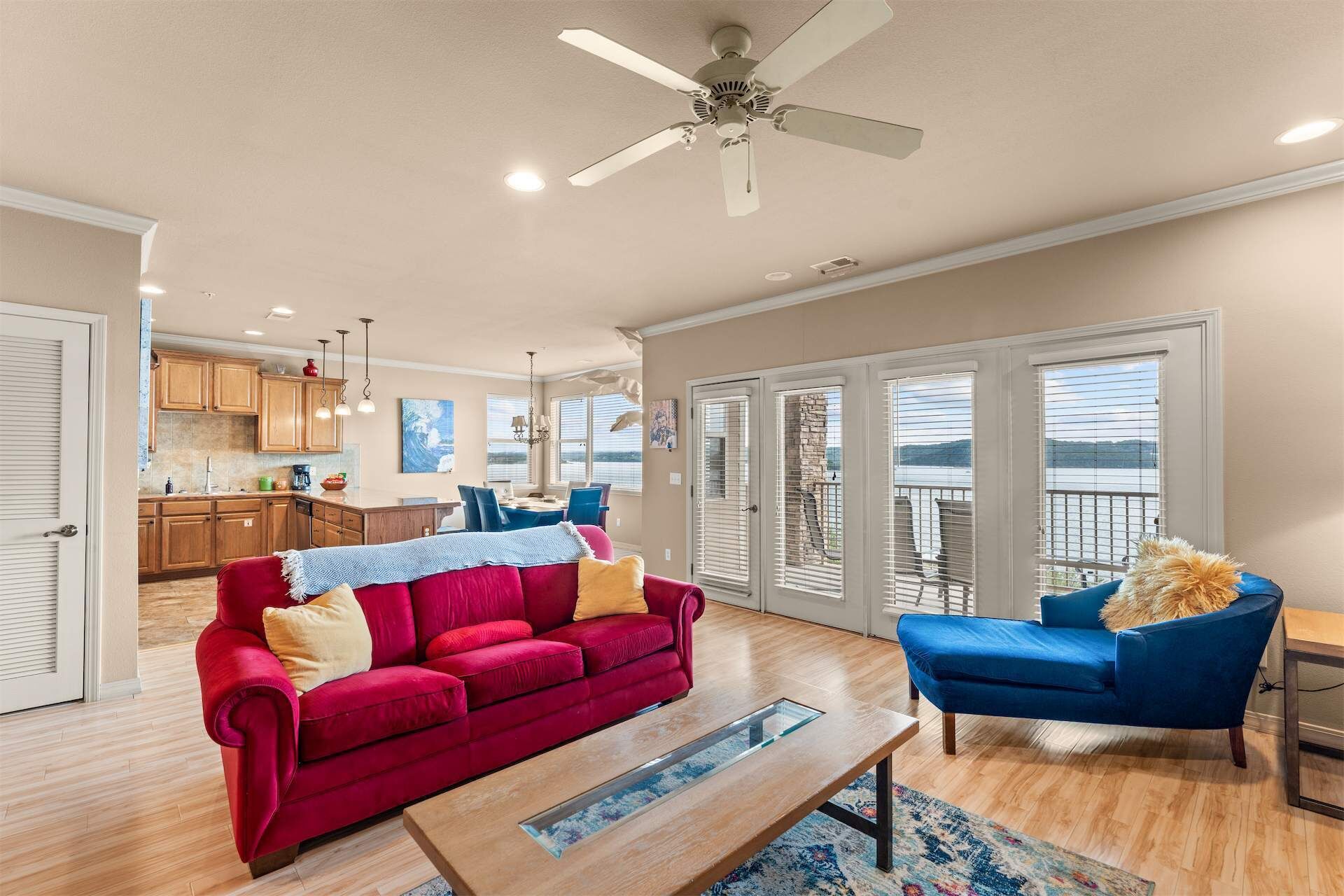 Uma sala de estar ampla com um sofá vermelho, uma poltrona azul e uma mesa de centro de madeira.