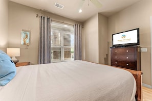 A hotel room with a bed, a television on a dresser, a window with blinds, and a painting on the wall. - Yakov's Hideaway - Lakefront (Hollister)