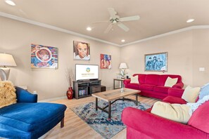 A living room with a red sofa, blue sofa, a coffee table, and a TV on a stand. - Yakov's Hideaway - Lakefront (Hollister)