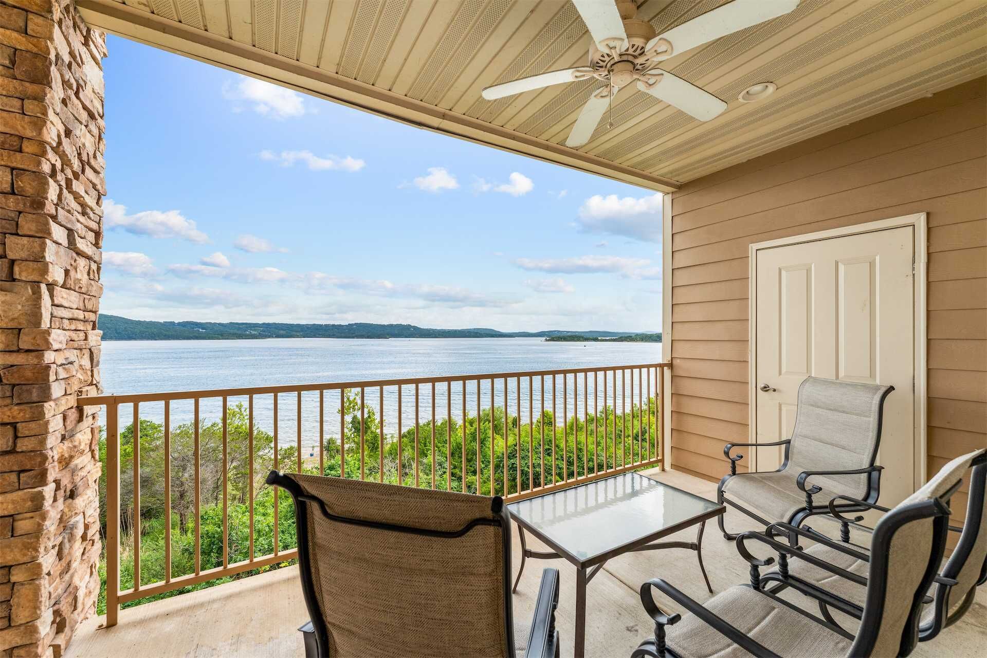 A balcony with a table and chairs, overlooking a body of water and distant land.