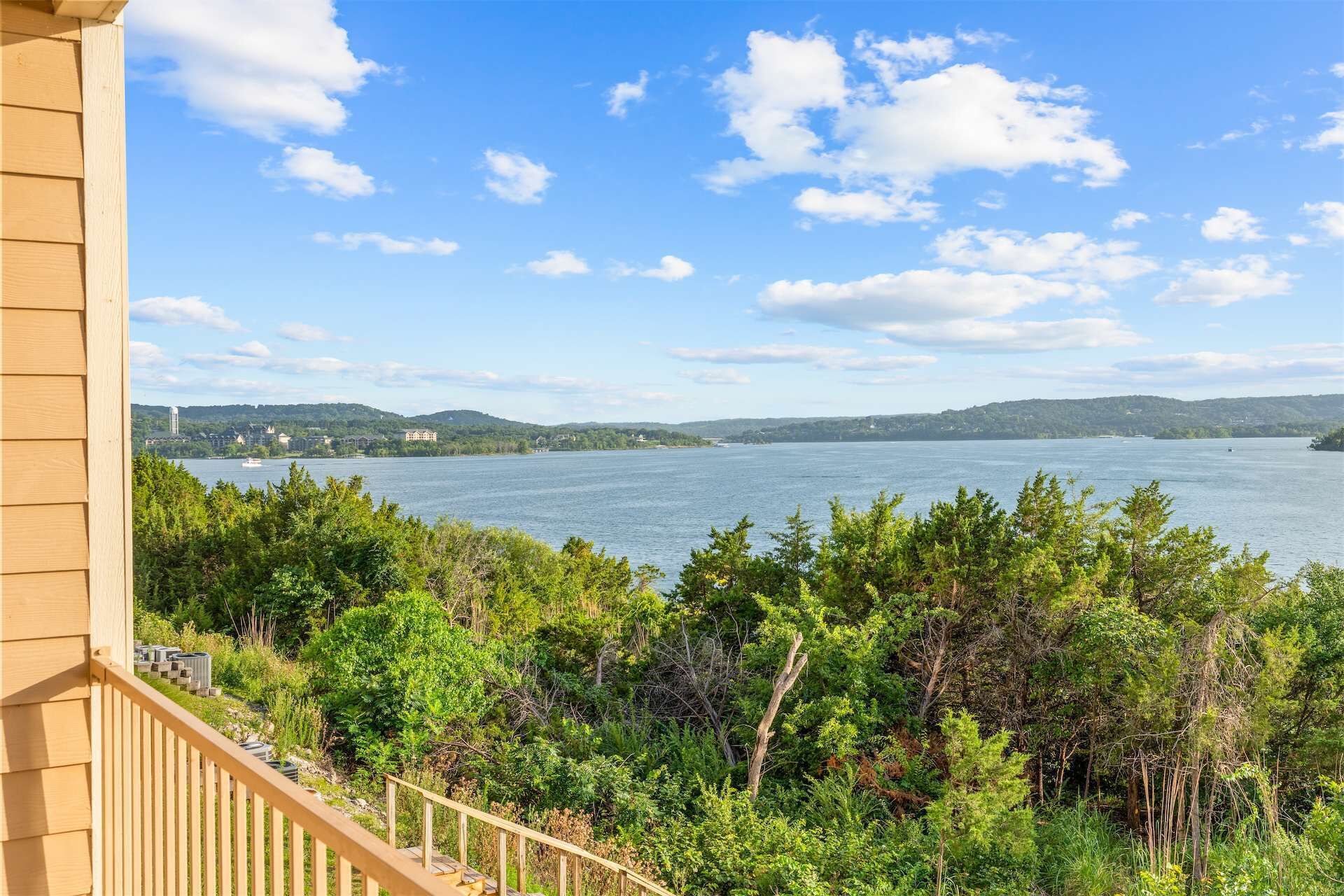 Un balcón con vistas a un lago, rodeado de vegetación exuberante.