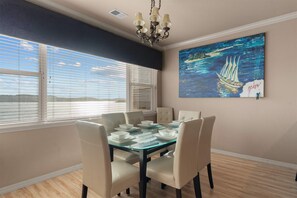 A dining area with a glass table, white chairs, and a painting of a sailboat on the wall. - Yakov's Retreat - Pool Access (Hollister)