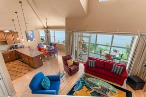 A spacious living area with a red sofa, a blue armchair, and a glass coffee table. - The Smirnoff Suite - 3bdr (Hollister)