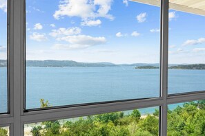 Vista pela janela, com céu claro e água calma, provavelmente de um quarto de hotel.