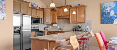 Una cocina moderna con armarios de madera, electrodomésticos de acero inoxidable y una isla central con taburetes de bar.