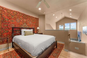 A bedroom with a large bed, a ceiling fan, a window with a view, and a patterned wall. - The Smirnoff Suite - 3bdr (Hollister)