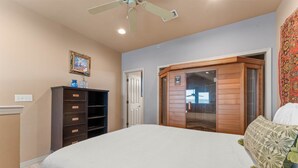 Quarto com uma cama grande, guarda-roupa de madeira, ventilador de teto e janela com vista.
