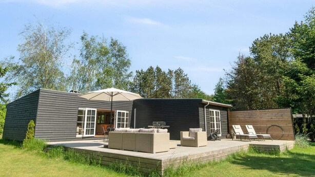 A modern outdoor living space with a patio, seating area, and a covered section. - 5 Star Holiday Home in Graested (Graested)