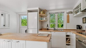 A kitchen with white cabinetry, a wooden countertop, a window with a view of greenery, and a built-in oven. - 5 Star Holiday Home in Graested (Graested)