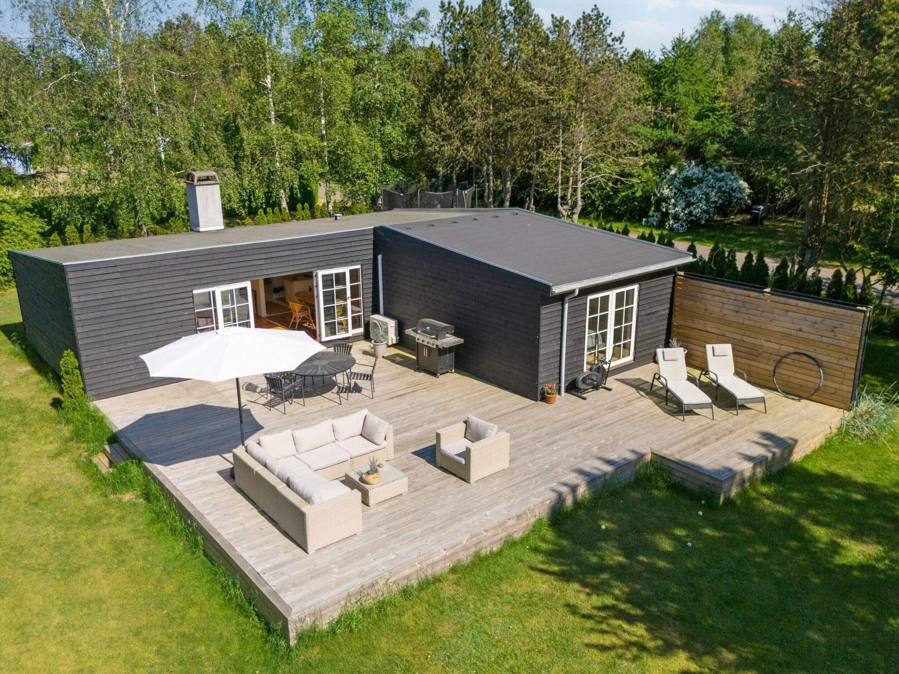 A modern house with a deck, outdoor furniture, and a barbecue area.
