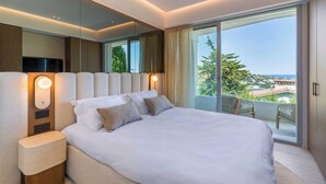Ein modernes Hotelzimmer mit einem großen Bett, einem Nachttisch, einem Spiegel und einem Balkon mit Blick.