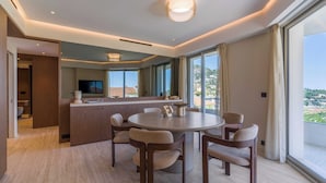 Ein modernes Hotelzimmer mit Essbereich, großem Fenster und Blick auf die Landschaft.