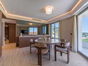 Ein modernes Hotelzimmer mit Essbereich, großem Fenster und Blick auf die Landschaft.