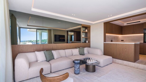 Ein modernes Wohnzimmer mit einer Eckcouch, einem runden Couchtisch und Blick auf die Stadt.