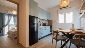 Una cocina moderna con refrigerador, estufa y comedor con sillas y mesa.
